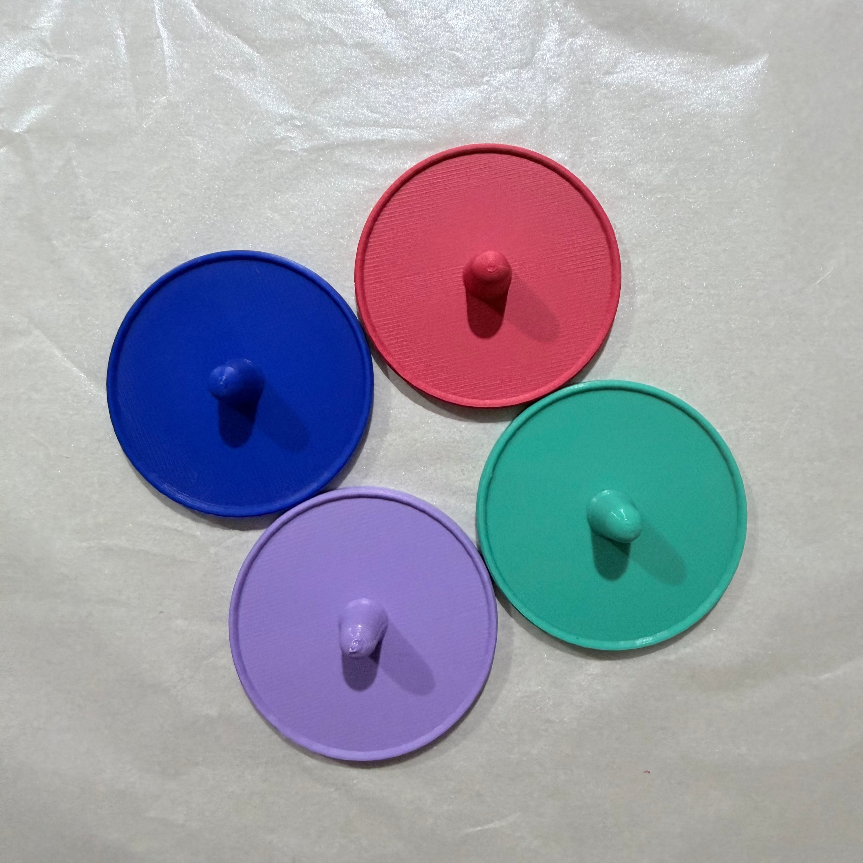 Four colorful kong stands (blue, red, green, purple) on a white background